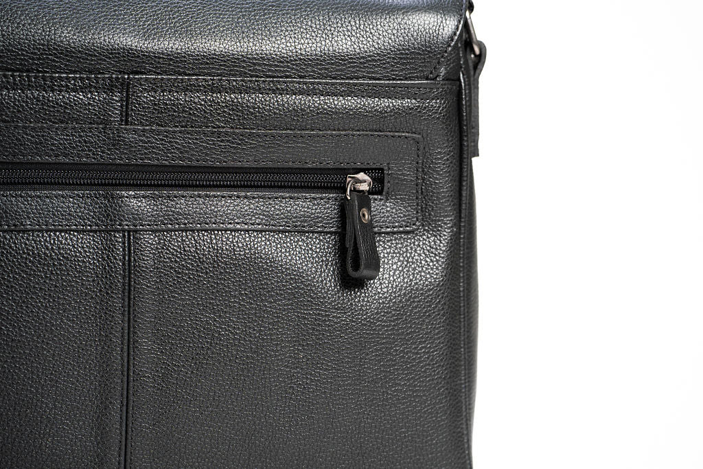 Close-up of an exterior zipper pull and stitched pocket on the Artelio black leather crossbody bag