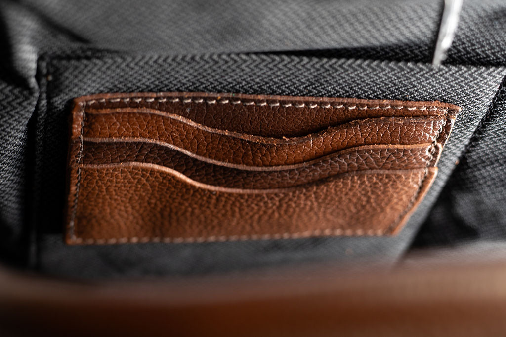 Close-up of the stitched leather card slots inside the Artelio brown leather backpack