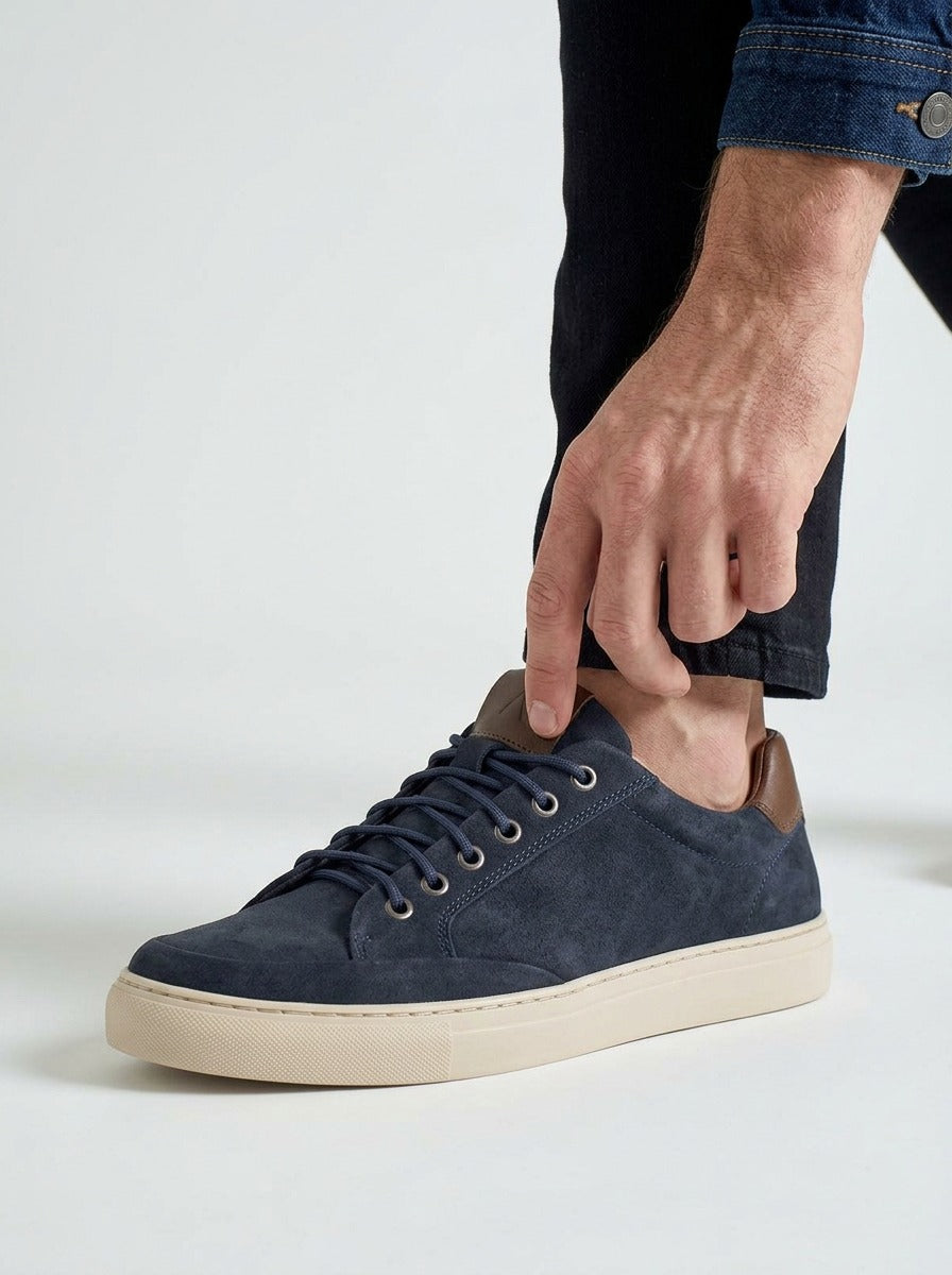 Lifestyle detail of the Artelio Elasticore navy nubuck sneaker being slipped on