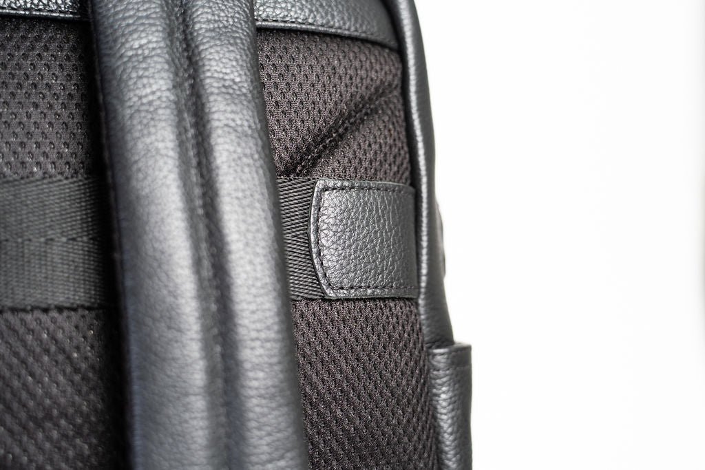 Close-up of the Artelio black leather backpack padded mesh back panel and shoulder strap attachment