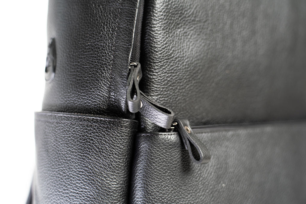 Close-up of the front zipper pulls and leather grain on the Artelio black leather backpack