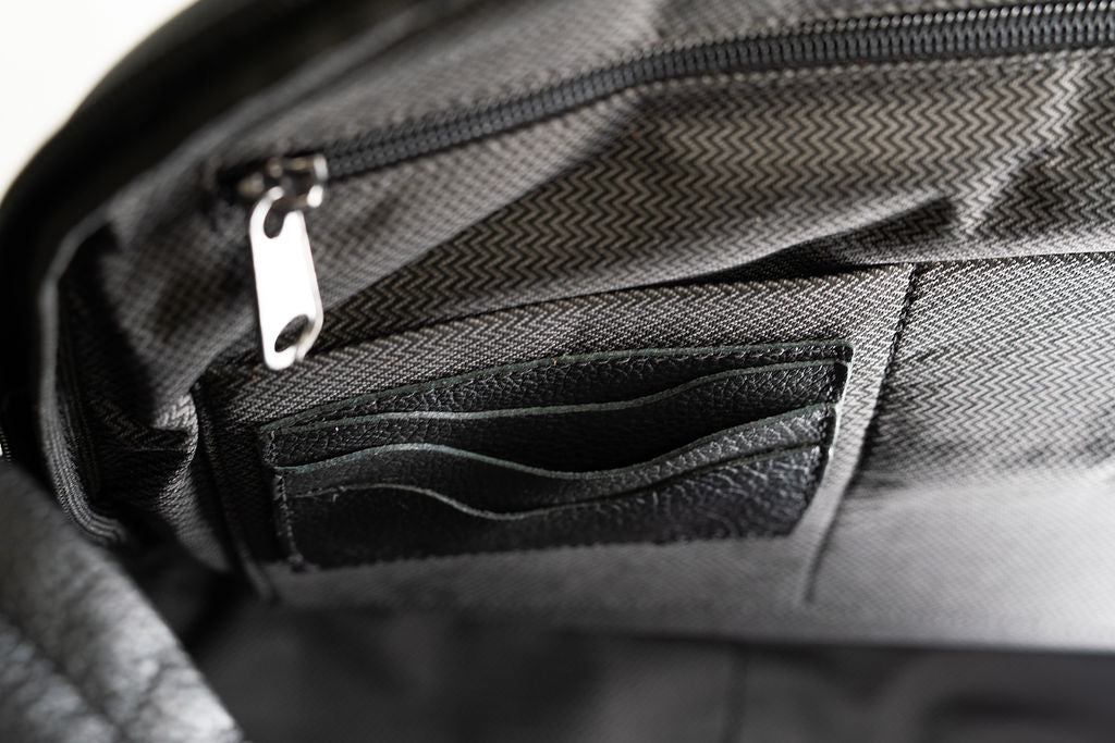 Interior organizer detail of the Artelio black leather backpack with card slots and a zippered pocket
