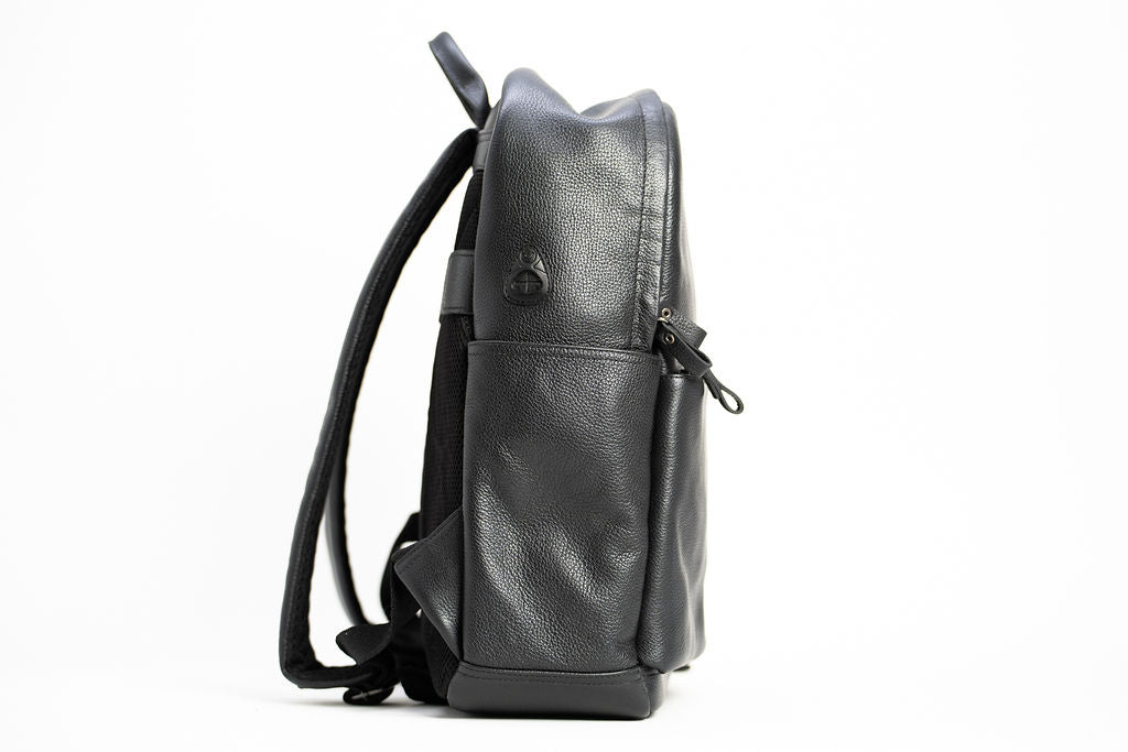 Side profile of the Artelio black leather backpack showing its slim shape shoulder straps and side pocket