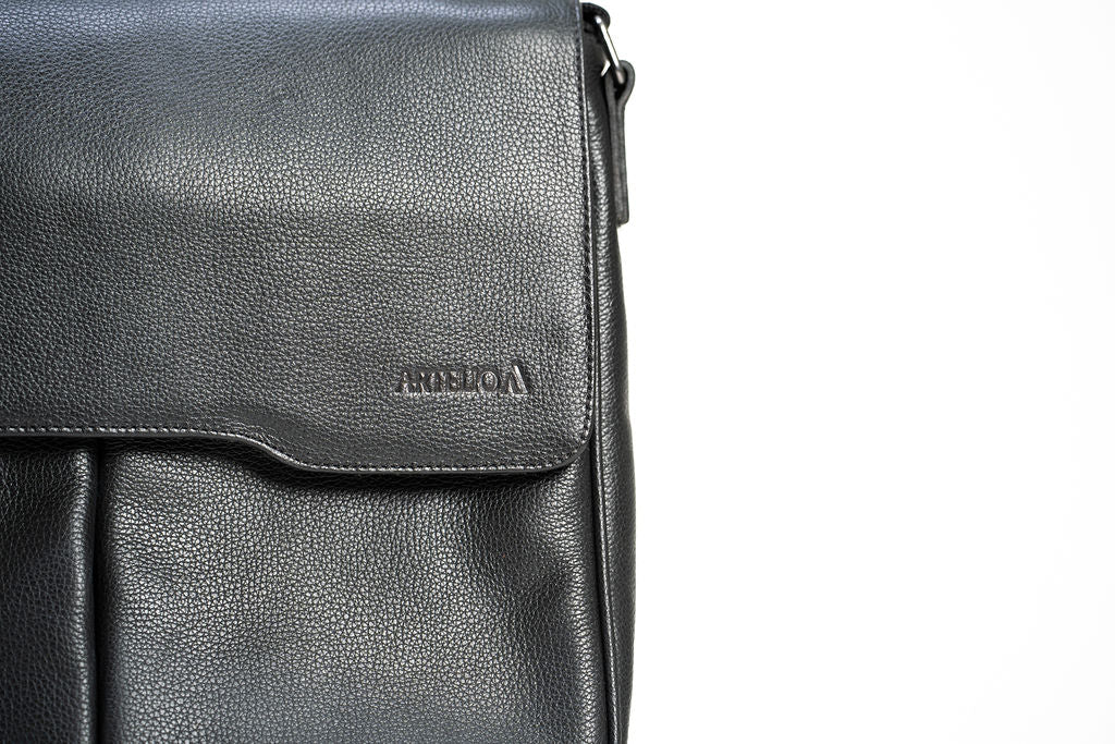 Close-up of the Artelio logo on the flap of the black leather crossbody bag