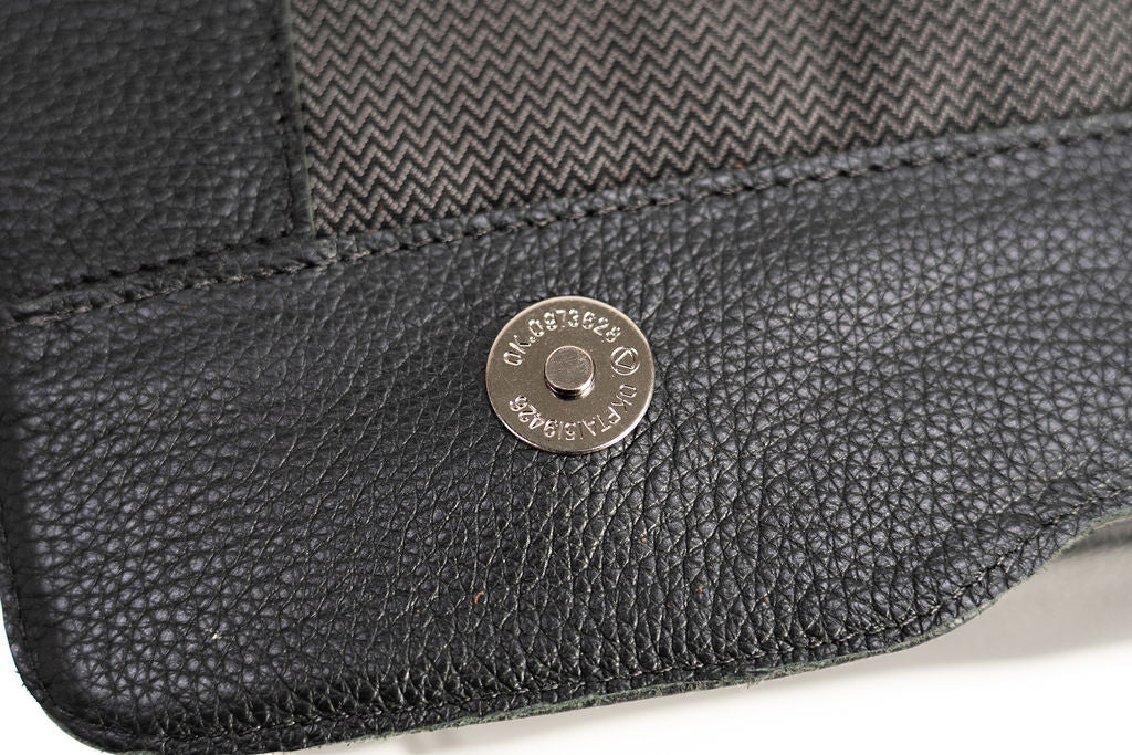 Close-up of the magnetic snap closure beneath the flap of the Artelio black leather crossbody bag