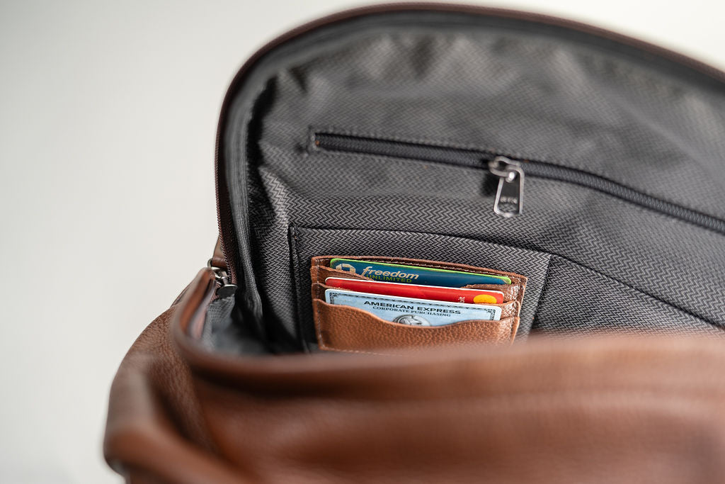 Open interior of the Artelio brown leather backpack showing card storage and the zippered organizer pocket