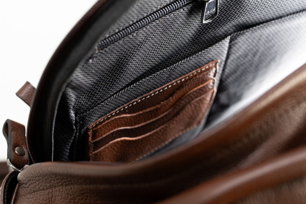 Open interior view of the Artelio brown leather backpack showing the organizer pockets and lining