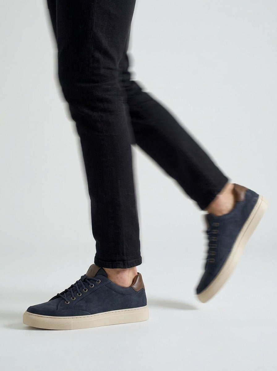 Lifestyle walking image of the Artelio Elasticore navy nubuck sneaker with black denim