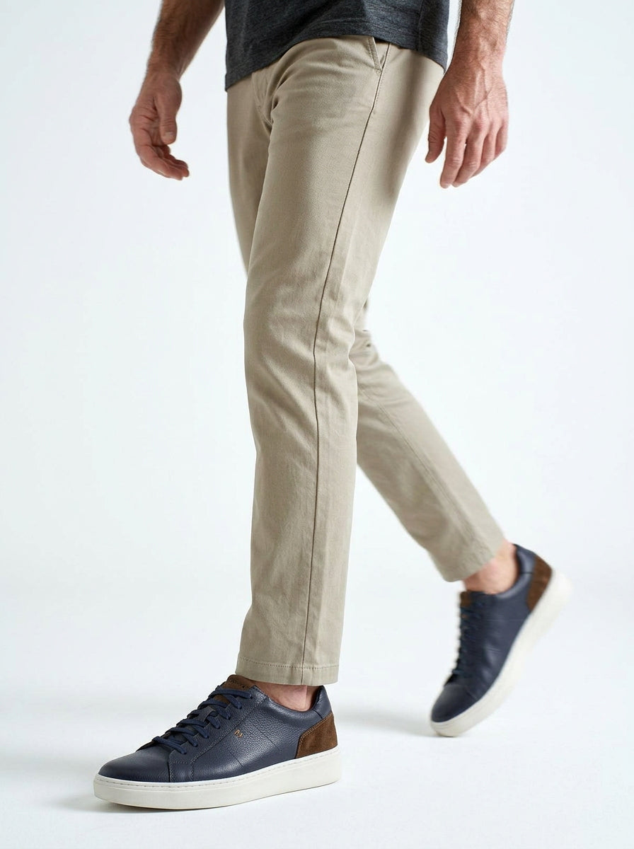 Lifestyle walking image of the Artelio Heritage indigo and chocolate leather sneaker in a smart casual outfit