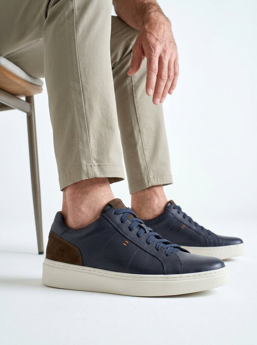 Lifestyle walking image of the Artelio Heritage indigo and chocolate leather sneaker in a smart casual outfit